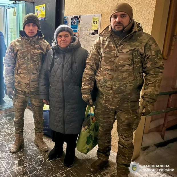 Двое мужчин в военной форме сопровождают женщину в зимней одежде