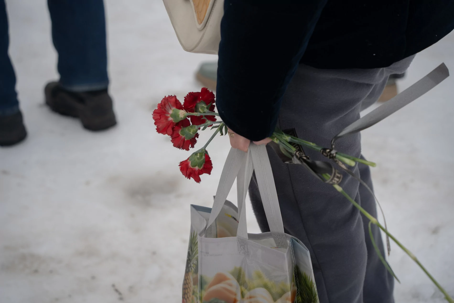Человек держит красные цветы и сумку